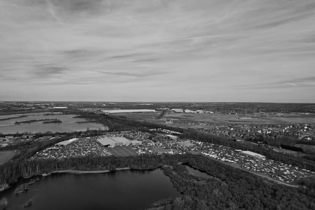 Black and white aerial photo of an industrial area with a lake in England, showcasing flat landscape.