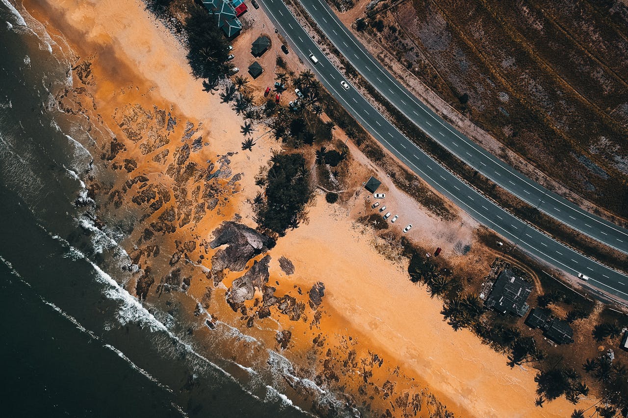 A breathtaking aerial shot of a coastline with a highway running parallel to the shore, showcasing nature and infrastructure.
