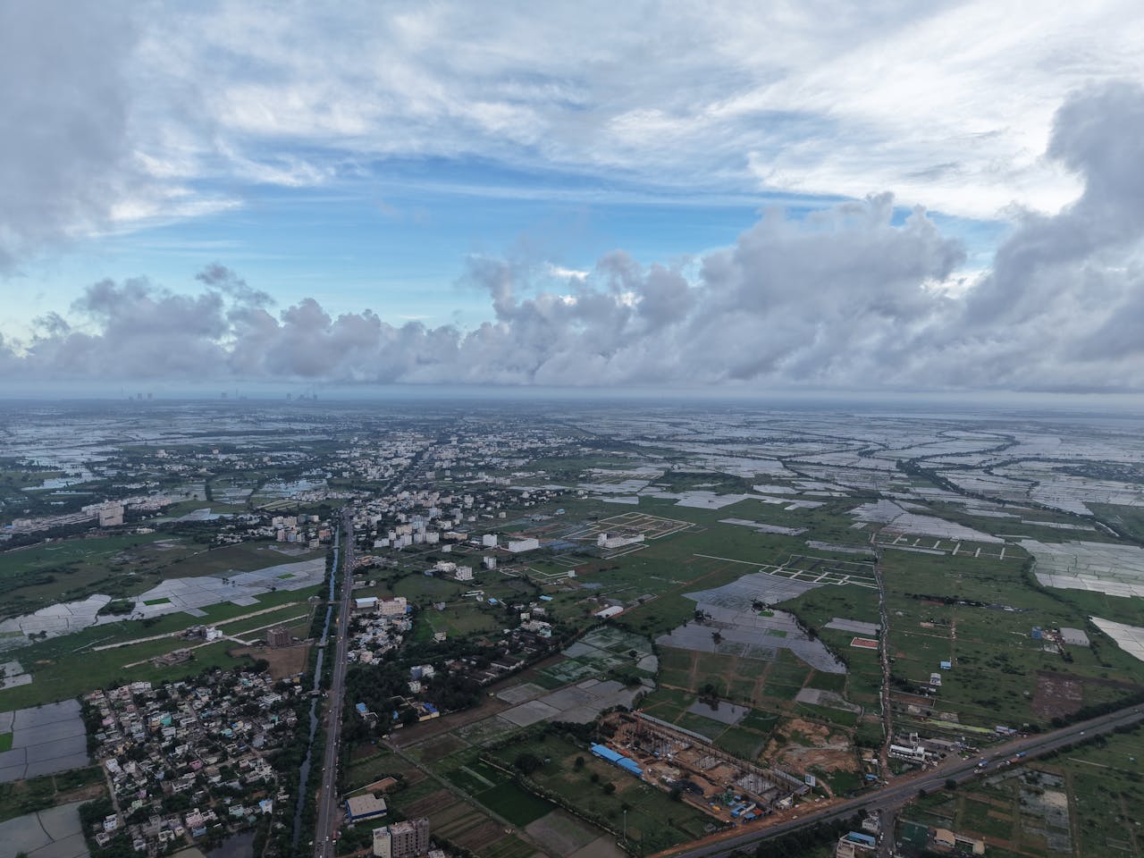 A breathtaking aerial shot capturing a vast countryside landscape with distant skyline views on a cloudy day.